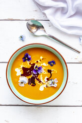 Bowl of creamed pumpkin soup garnished with edible flowers - SARF03986