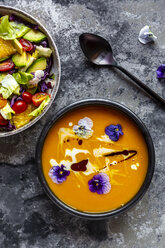 Bowl of mixed salad with edible flowers and bowl of creamed pumpkin soup garnished with edible flowers - SARF03990