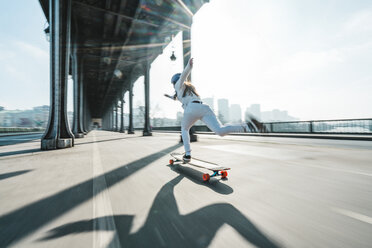 Unscharfe Bewegung der Frau Skateboarding unter Brücke in der Stadt gegen den Himmel - CAVF56760