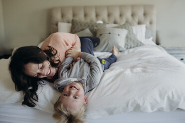 High angle view of happy mother playing with son while lying on bed at home - CAVF56778