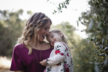 Cheerful mother carrying daughter on field - CAVF56800