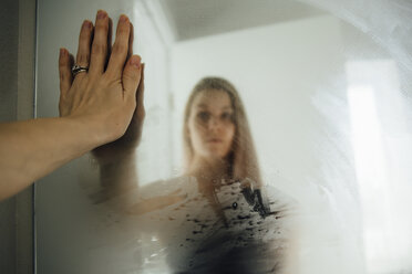 Woman reflecting on wet mirror at home - CAVF56815