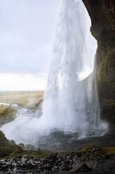 Blick auf den Wasserfall Seljalandsfoss über einer Felsformation bei bewölktem Himmel - CAVF56828