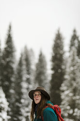 Seitenansicht einer Frau mit Rucksack vor dem Himmel in einem verschneiten Wald - CAVF56860