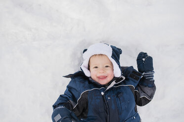 Overhead portrait of cute baby boy lying on snow - CAVF56887