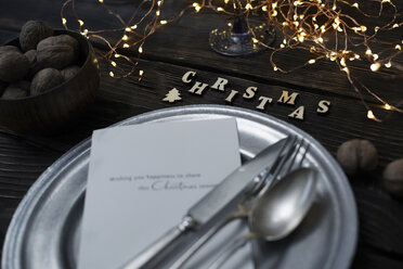 Hohe Winkelansicht von Besteck mit Teller von Walnüssen und Weihnachtsschmuck auf Holztisch - CAVF56909