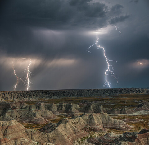 Hohe Winkel majestätischen Blick auf Felsformationen im Badlands National Park gegen Gewitter und Blitzschlag, lizenzfreies Stockfoto