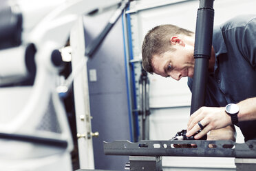 Serious male worker working on steel with machine at industry - CAVF56977