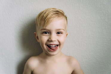 Close-up portrait of happy boy standing against wall at home - CAVF57006