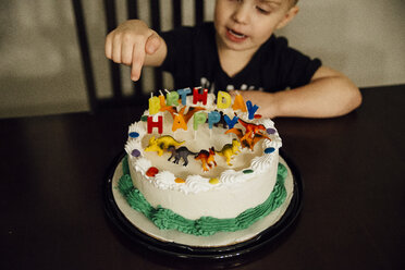 High angle view of boy sitting by birthday cake on chair at home - CAVF57007