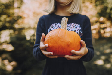 Midsection of girl holding pumpkin at field - CAVF57036