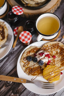 Nahaufnahme von Pfannkuchen mit Marmelade und Früchten auf einem Holztisch - CAVF57052