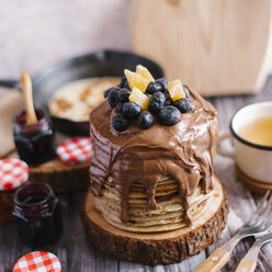 Stapel von Pfannkuchen mit Schokolade und Früchten auf Holz am Tisch - CAVF57054
