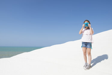 Mädchen fotografiert, während sie am Strand gegen den klaren blauen Himmel während des sonnigen Tages steht - CAVF57075