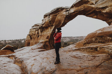 Side view of woman looking away while standing on rock formation against sky - CAVF57138