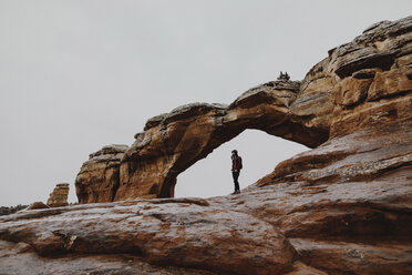 Side view of man standing on rock formation against sky - CAVF57139