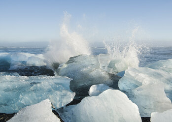 Scenic view of waves splashing on ice in sea against sky - CAVF57175