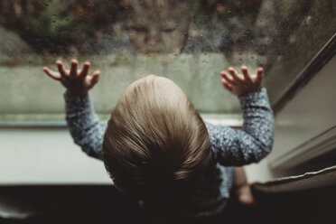 High angle view of girl looking through window at home - CAVF57197