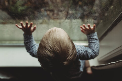 Hoher Blickwinkel eines Mädchens, das durch ein Fenster zu Hause schaut - CAVF57197