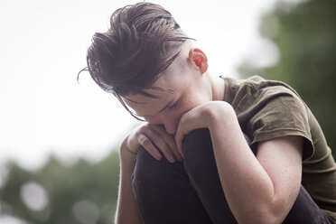 Nahaufnahme eines gegen den Himmel kauernden Teenagers - CAVF57213