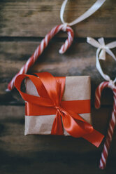 High angle view of Christmas present with candy canes on wooden table - CAVF57268