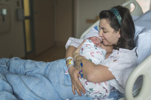 Mutter küsst ihren neugeborenen Sohn und entspannt sich auf dem Bett im Krankenhaus - CAVF57275