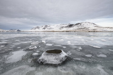Blick auf einen zugefrorenen See vor schneebedeckten Bergen und bewölktem Himmel - CAVF57305