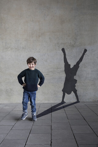 Deutschland, Düsseldorf, Porträt eines lächelnden kleinen Jungen und Schatten des Düsseldorfer Riesenrads an der Wand, lizenzfreies Stockfoto