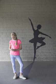 Blondes Mädchen mit Smartphone und Schatten der Ballerina im Hintergrund - PSTF00266