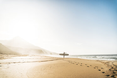 Mann mit Surfbrett steht am Strand gegen den Himmel bei nebligem Wetter - CAVF57366