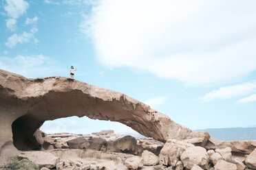 Mid distance view of woman standing on rock formation against sky - CAVF57367