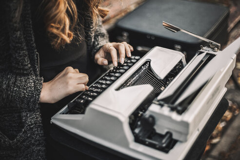 Mittelteil einer Schriftstellerin, die auf einer Parkbank sitzend eine Schreibmaschine benutzt - CAVF57370