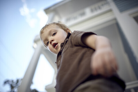 Niedriger Winkel Porträt eines kleinen Jungen stehend durch Gebäude, lizenzfreies Stockfoto