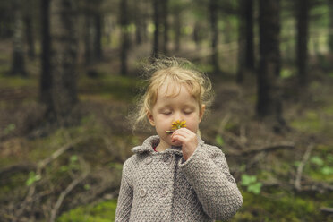 Nettes Mädchen mit geschlossenen Augen riecht Blume im Wald - CAVF57446