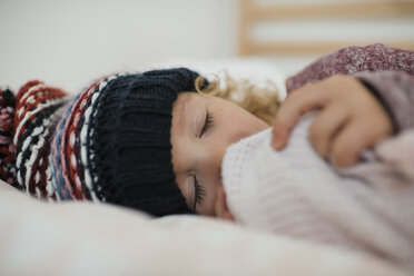 Nahaufnahme eines süßen Mädchens mit Strickmütze, das zu Hause auf dem Bett schläft - CAVF57454