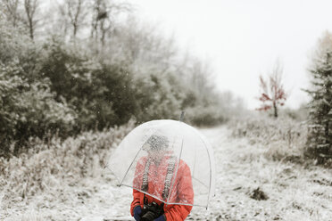 Junge mit Regenschirm im Wald stehend im Winter - CAVF57459