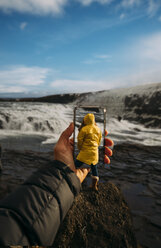 3D-Montage eines Mannes, der ein Smartphone-Foto von der isländischen Landschaft macht, und einer Frau, die einen gelben Regenmantel trägt - OCMF00123