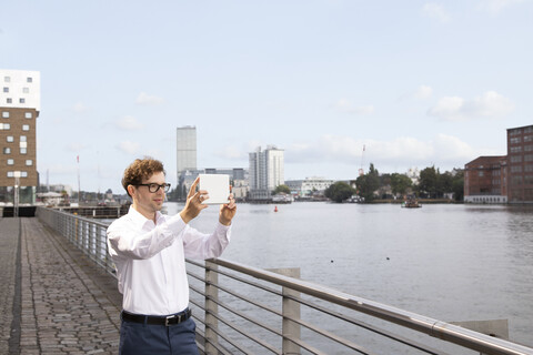 Deutschland, Berlin, Geschäftsmann beim Fotografieren mit digitalem Tablet, lizenzfreies Stockfoto