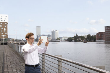 Germany, Berlin, businessman taking photo with digital tablet - FKF03107