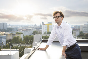 Germany, Berlin, portrait of businessman on roof terrace looking at view - FKF03125