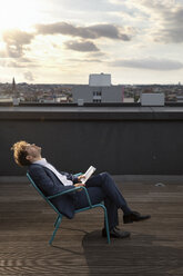 Germany, Berlin, businessman relaxing on roof terrace at sunset - FKF03132