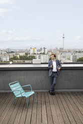 Germany, Berlin, businessman relaxing on roof terrace with a drink - FKF03134