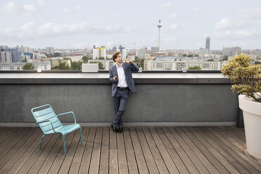 Deutschland, Berlin, Geschäftsmann bei einem Drink auf der Dachterrasse nach der Arbeit - FKF03135