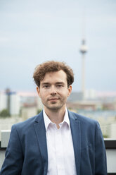 Deutschland, Berlin, Porträt eines Geschäftsmannes mit Bartstoppeln und lockigem braunem Haar auf einer Dachterrasse - FKF03136