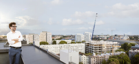 Deutschland, Berlin, Geschäftsmann steht auf einer Dachterrasse und betrachtet die Aussicht, lizenzfreies Stockfoto