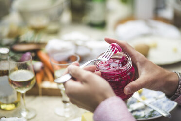 Cropped image of man removing pickle from jar at table during dinner party - MASF09712
