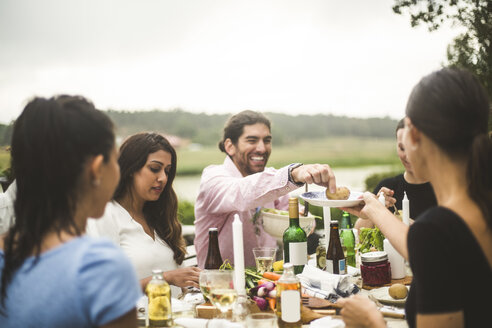 Männliche und weibliche Freunde genießen das Abendessen während einer Party im Hinterhof - MASF09720