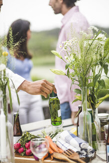 Cropped image of man holding beer bottle over dining table during dinner party in backyard - MASF09742