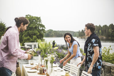 Glückliche multiethnische Freunde decken den Tisch für eine Dinnerparty im Hinterhof gegen den klaren Himmel - MASF09745