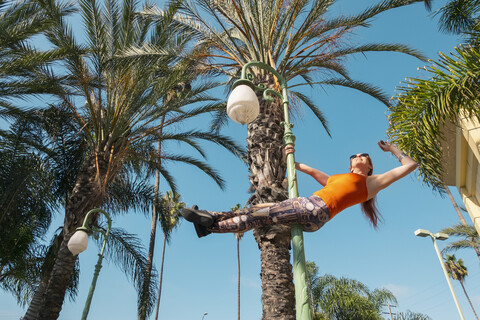 USA, Kalifornien, Los Angeles, Marina Del Rey, Sportliche Frau auf einem Laternenpfahl, Poledance, lizenzfreies Stockfoto